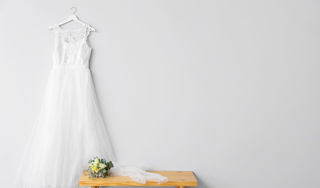 Robe de mariée suspendue près d'un bouquet de fleurs sur une table en bois