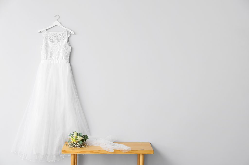 Robe de mariée suspendue près d'un bouquet de fleurs sur une table en bois