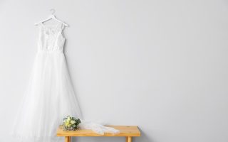 Robe de mariée suspendue près d'un bouquet de fleurs sur une table en bois