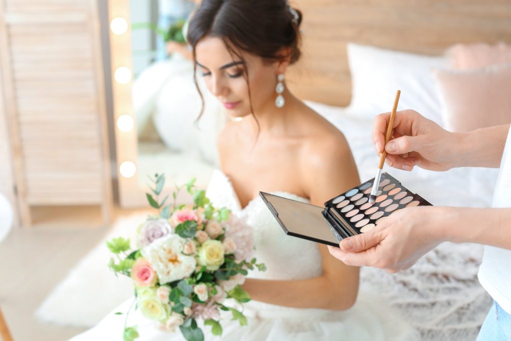 Maquilleuse professionnelle appliquant un maquillage naturel et lumineux sur une future mariée
