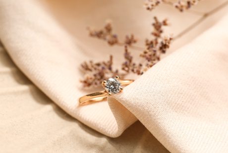 Bague de fiançailles en or rose sertie d'un diamant solitaire, posée sur un tissu beige