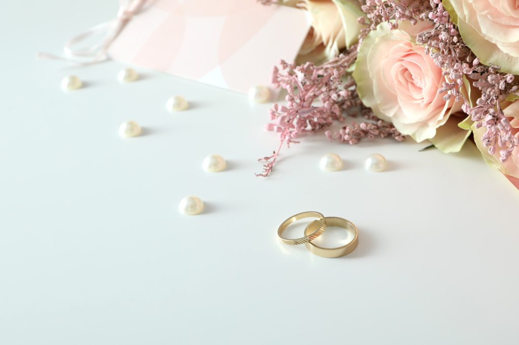 Deux alliances de mariage dorées posées sur un fond blanc avec accessoires de mariage