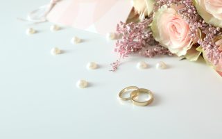 Deux alliances de mariage dorées posées sur un fond blanc avec accessoires de mariage