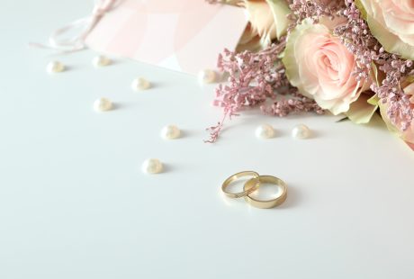 Deux alliances de mariage dorées posées sur un fond blanc avec accessoires de mariage