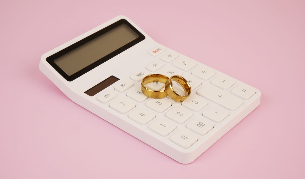 Alliances de mariage posées sur une calculatrice : budget et prix d'un mariage en Belgique