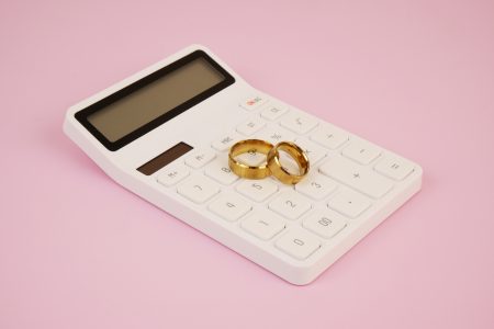 Alliances de mariage posées sur une calculatrice : budget et prix d'un mariage en Belgique