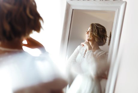 Future mariée souriante devant un miroir, dans une lumière douce du matin
