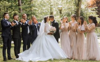 Les mariés posant en pied avec leurs amis, tous en tenue élégante
