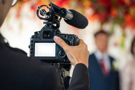 Vidéaste filmant la cérémonie d'un mariage avec une caméra équipée d'un micro