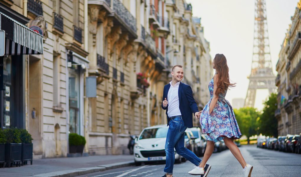 Couple traversant une rue parisienne avec la tour Eiffel en arrière-plan
