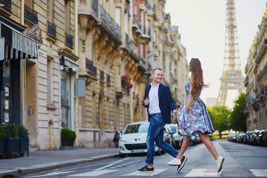 Couple traversant une rue parisienne avec la tour Eiffel en arrière-plan