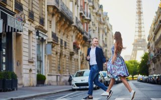 Couple traversant une rue parisienne avec la tour Eiffel en arrière-plan