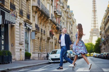 Couple traversant une rue parisienne avec la tour Eiffel en arrière-plan