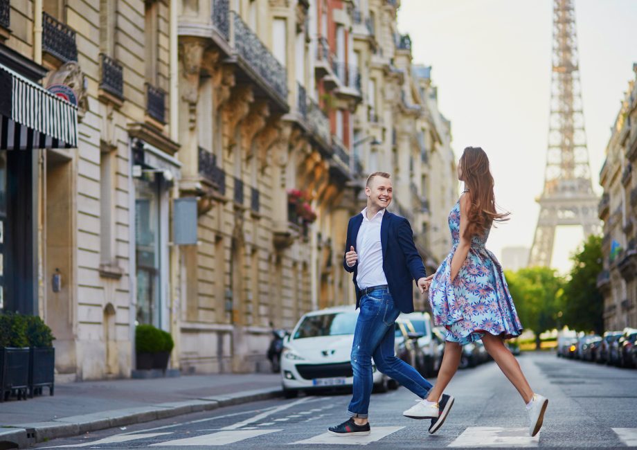 Couple traversant une rue parisienne avec la tour Eiffel en arrière-plan